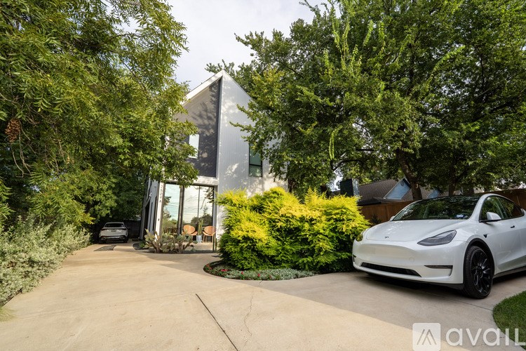A white Tesla car is parked in a driveway.