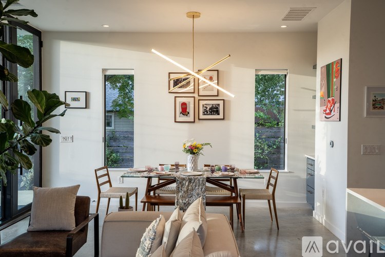 A living room with a brown couch, a glass table, and a vase of flowers.