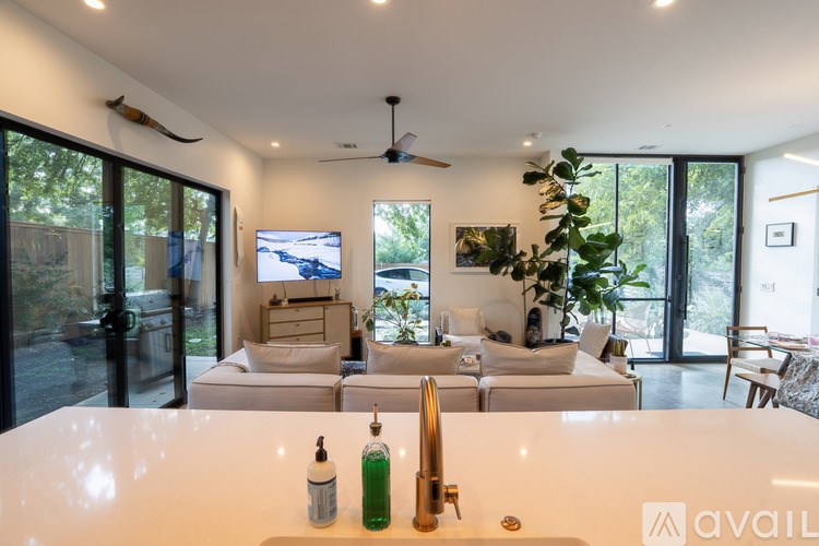 A modern kitchen with a white countertop and a sink with a green bottle of dish soap.