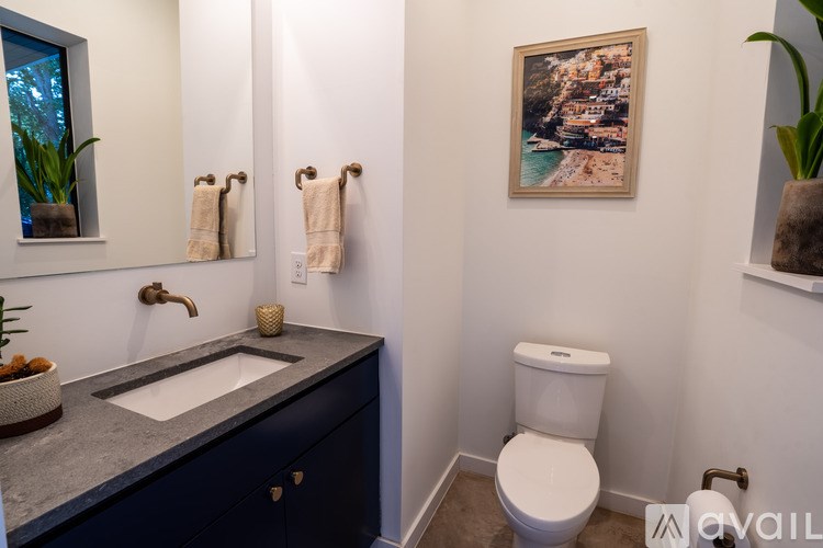 A bathroom with a toilet, sink, and a painting on the wall.