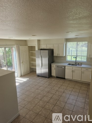 A kitchen with white cabinets and a refrigerator.