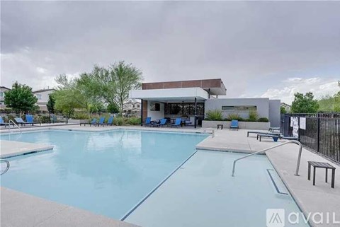 A large outdoor swimming pool with lounge chairs and a building in the background.