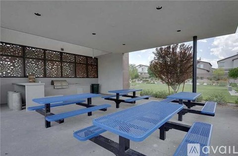 A covered outdoor picnic area with blue tables and benches.