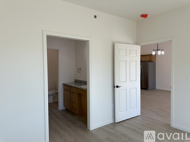 A room with a white door and a small kitchen area with a sink and cabinets.