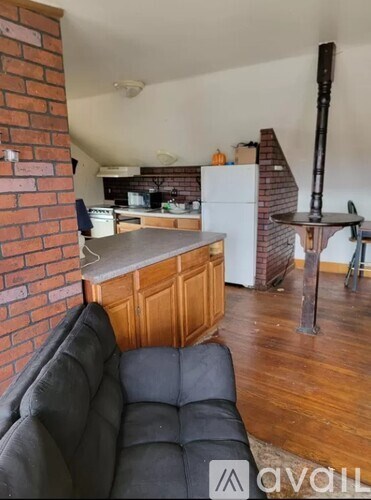 A living room with a black couch and a brick wall.