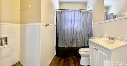 A bathroom with a toilet, sink, and shower curtain.