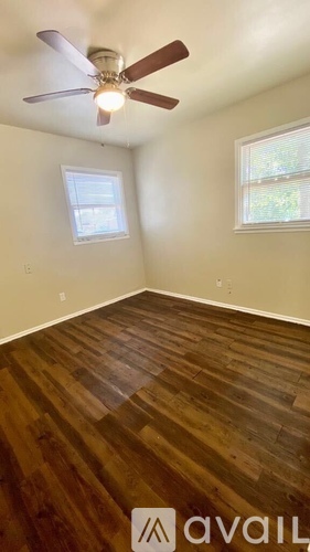 A room with a ceiling fan and wooden flooring.