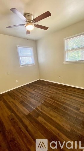 A room with a ceiling fan and wooden flooring.