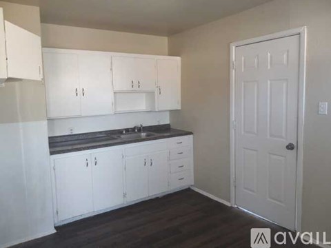 A kitchen with white cabinets and a black countertop.