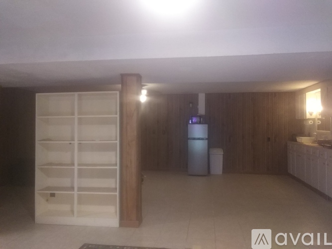 A kitchen with a refrigerator, a sink, and a wooden cabinet.