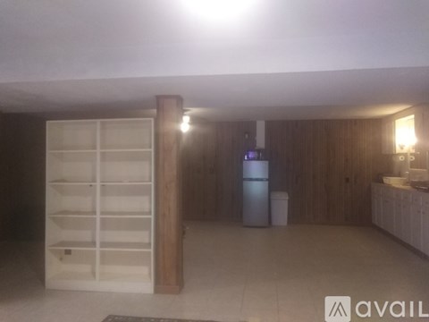 A kitchen with a refrigerator, a sink, and a wooden cabinet.