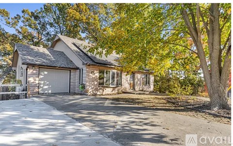 A house with a driveway and trees in the background.