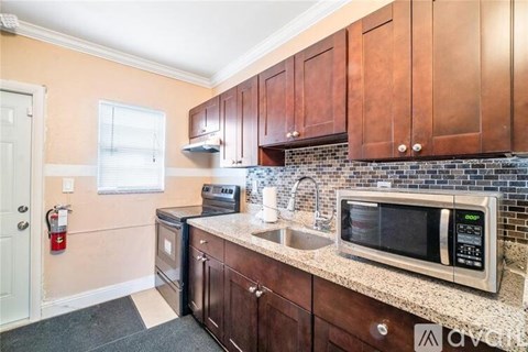 A kitchen with brown cabinets and a black microwave.