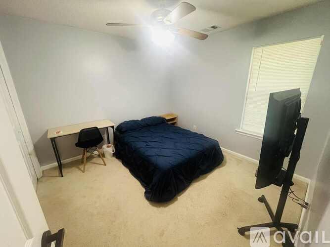 A bedroom with a bed, desk, and television.