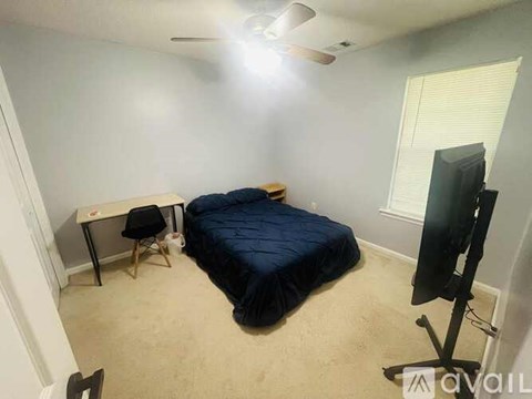 A bedroom with a bed, desk, and television.