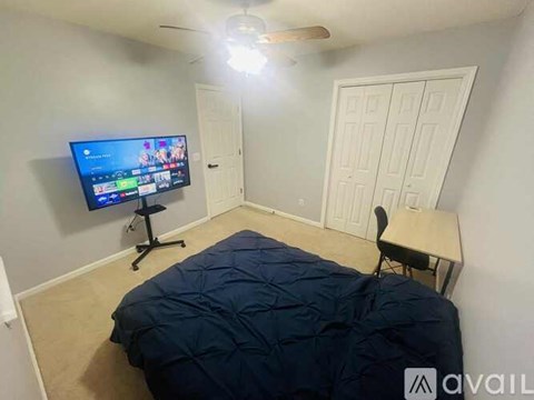 A bedroom with a bed, desk, and television.