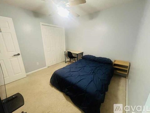 A bedroom with a bed, chair, and a fan.