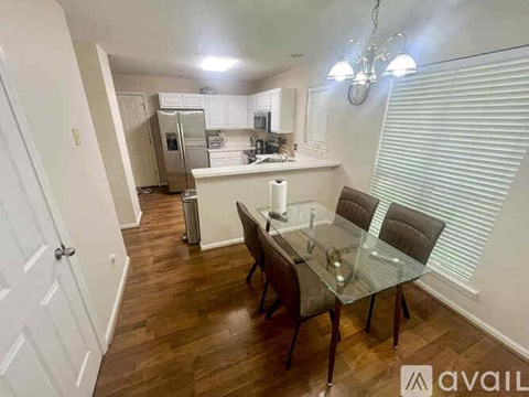 A dining room with a glass table and chairs is shown.