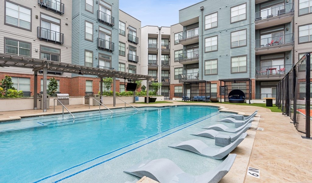 A large outdoor swimming pool surrounded by apartment buildings.