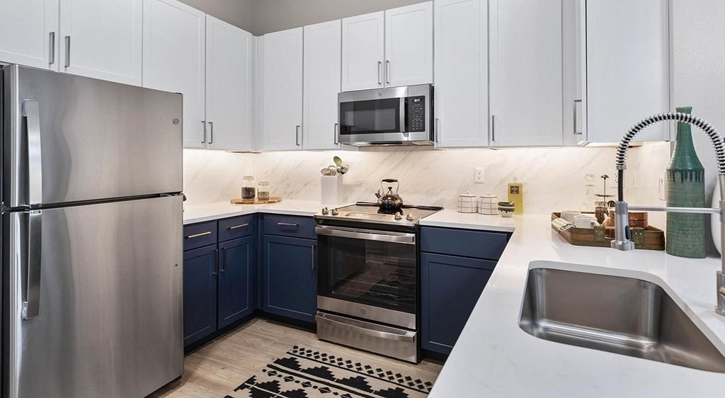 A modern kitchen with a stainless steel refrigerator and a sink.