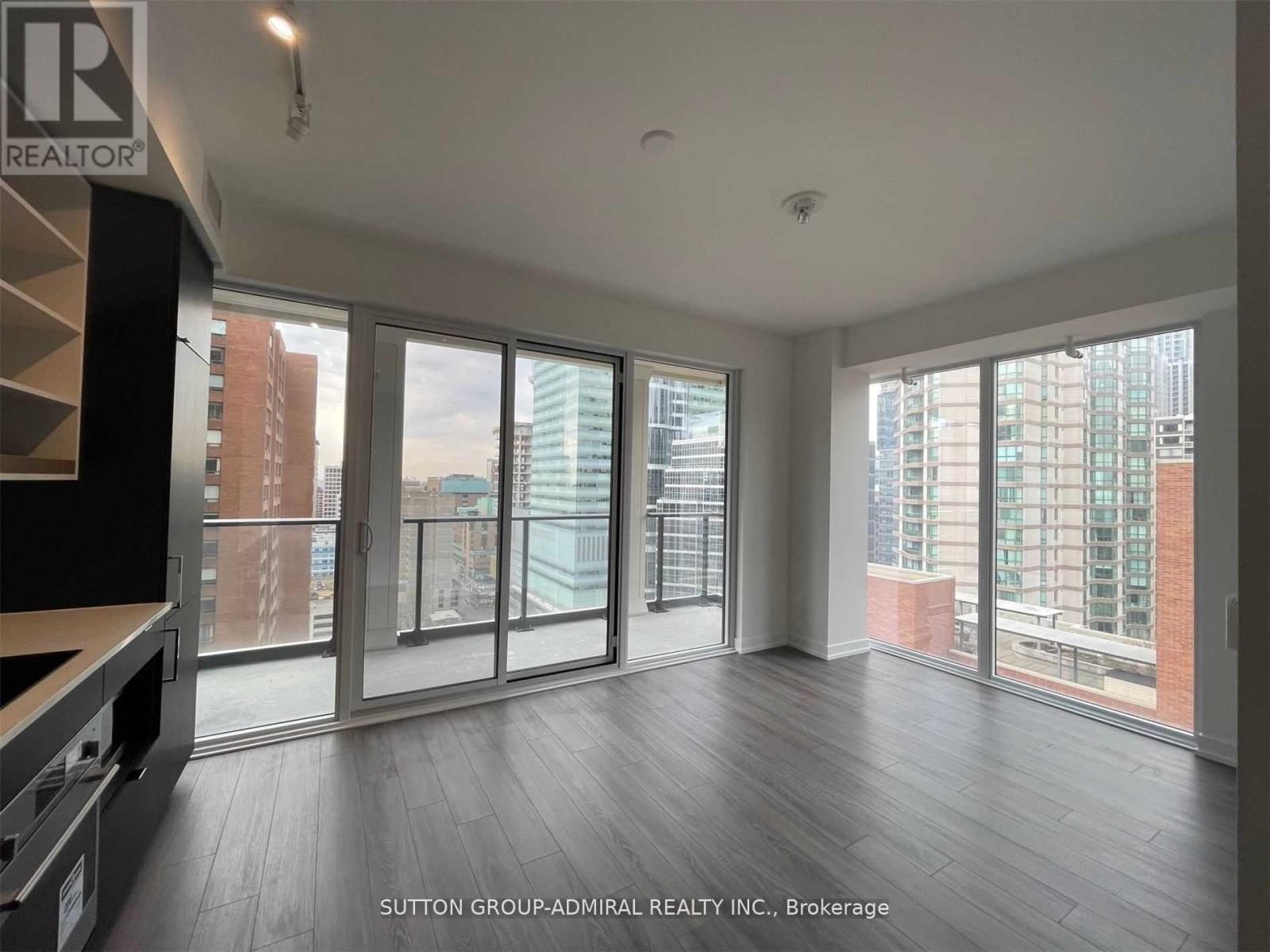 A spacious room with large windows and wooden flooring.