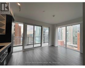A spacious room with large windows and wooden flooring.
