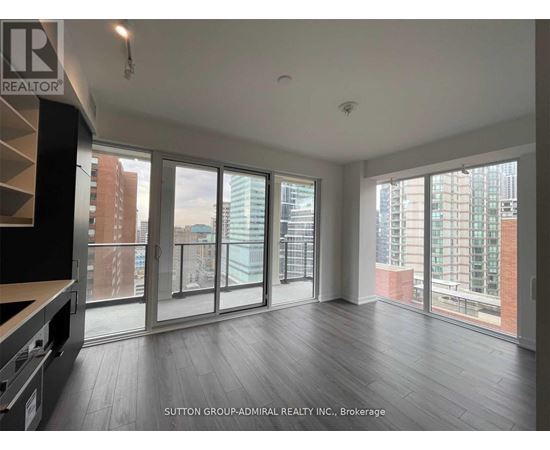 A spacious room with large windows and wooden flooring.
