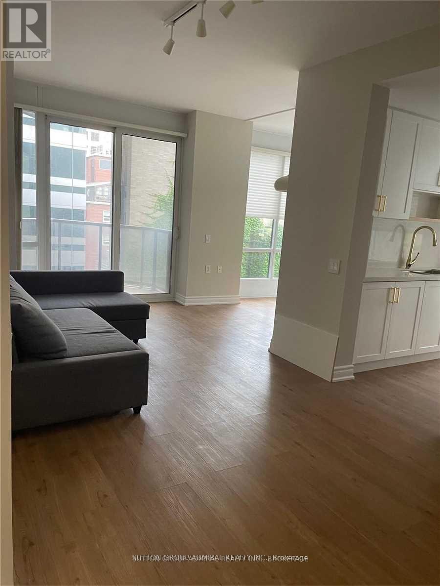 A living room with a grey couch and wooden floors.