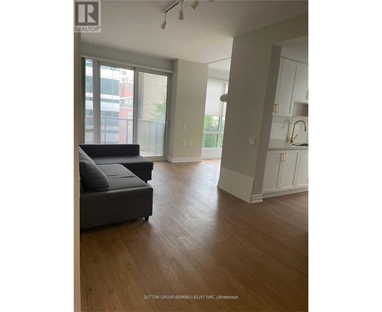 A living room with a grey couch and wooden floors.