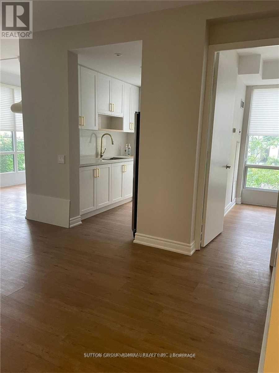 A room with wooden floors and white walls, with a doorway leading to another room.