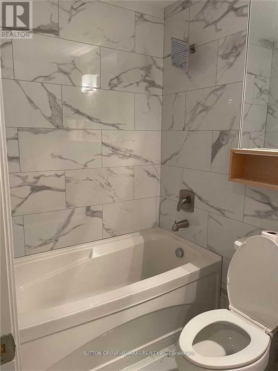 A bathroom with a marble tile wall and a white toilet.