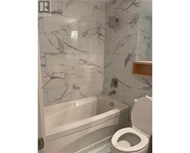 A bathroom with a marble tile wall and a white toilet.