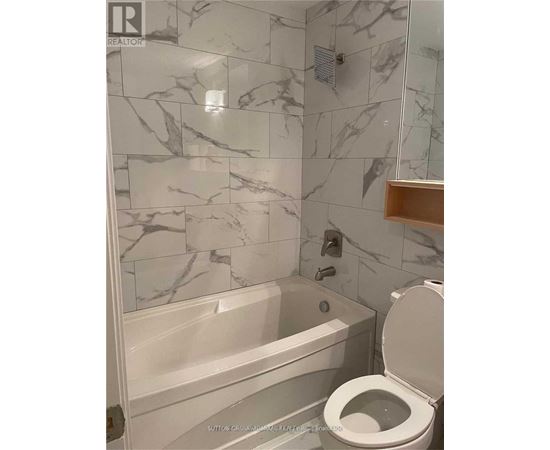 A bathroom with a marble tile wall and a white toilet.