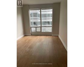 A room with wooden flooring and a large window overlooking a building.