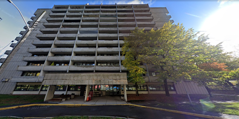 A tall concrete building with a tree in front of it.
