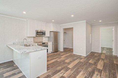 A kitchen with a white counter top and wooden floors.