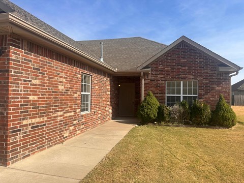 A brick house with a brown roof and a small front yard.