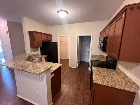 A kitchen with brown cabinets and a granite countertop.