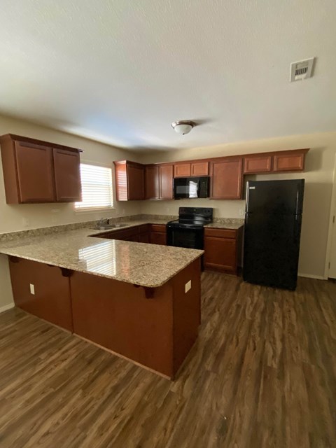 A kitchen with brown cabinets and a black refrigerator.