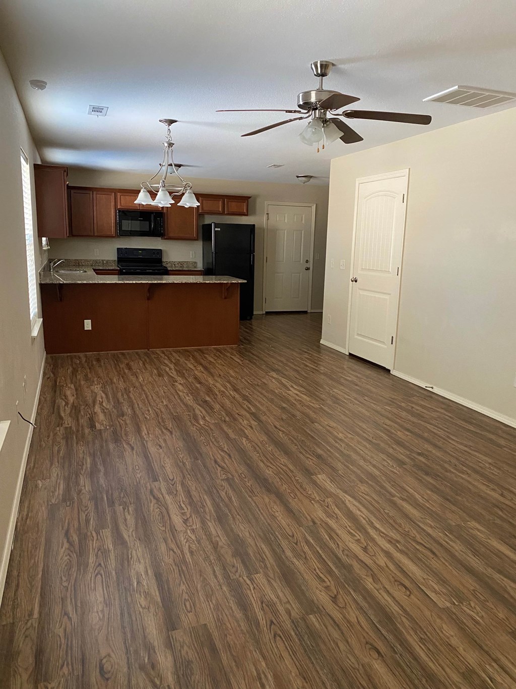 A kitchen with wooden floors and a ceiling fan.