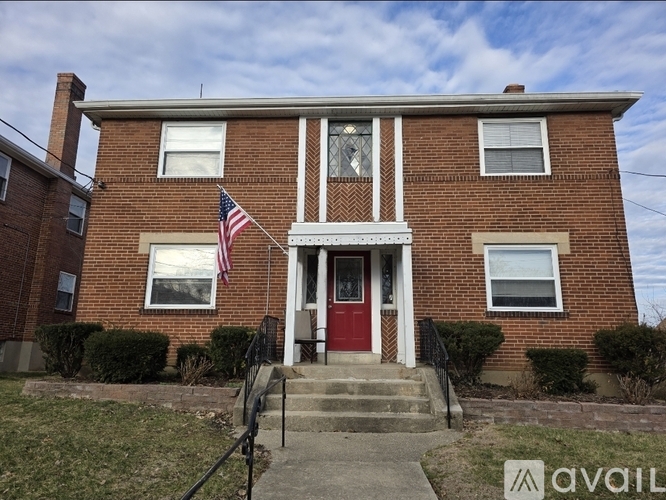 A brick house with a red door and an American flag on the front.