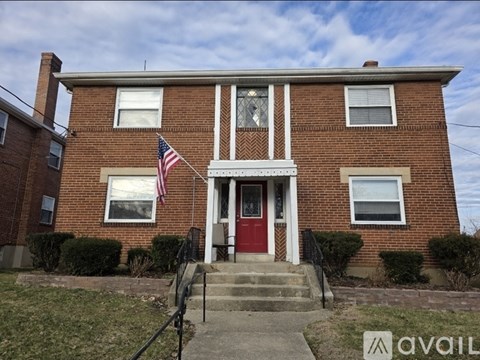 A brick house with a red door and an American flag on the front.