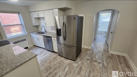 A kitchen with a refrigerator, sink, and cabinets.