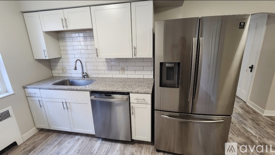 A kitchen with white cabinets and a stainless steel refrigerator.