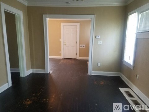 A room with a white door and a window on the right side.