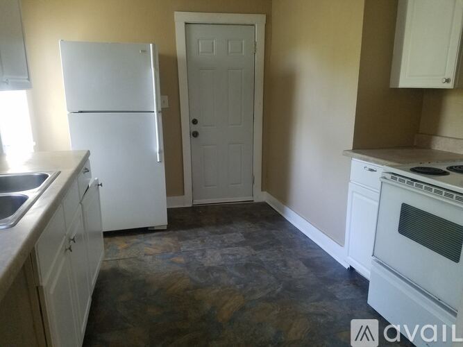 A kitchen with a white fridge, white door, and a white oven.