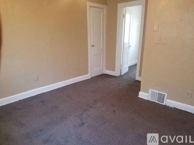 A room with a carpeted floor and two doors.