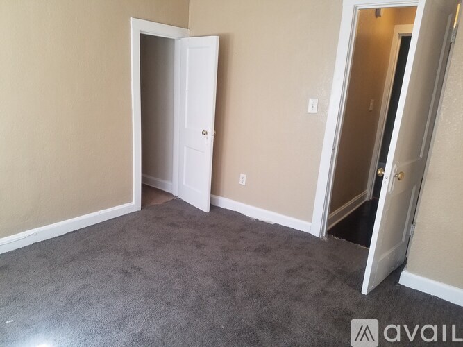 A room with a carpeted floor and two open doors.