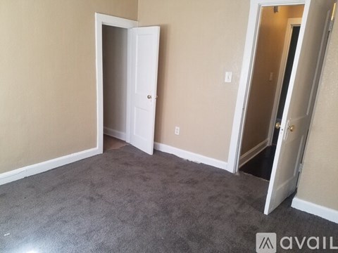 A room with a carpeted floor and two open doors.