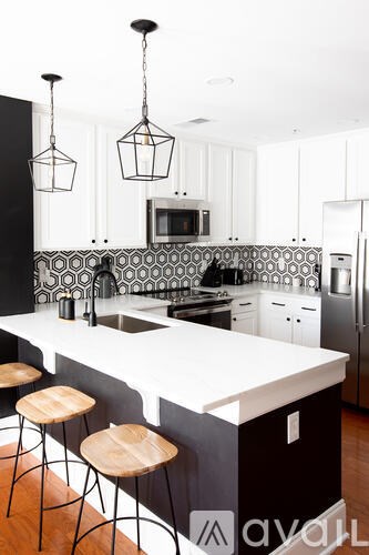 A kitchen with a white counter top and black and white tiles.